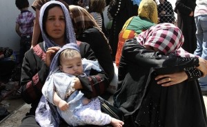 Families fleeing the violence in the Iraqi city of Mosul wait at a checkpoint in outskirts of Arbil