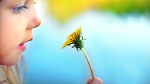 Cute girl with dandelion, focus on dandelion